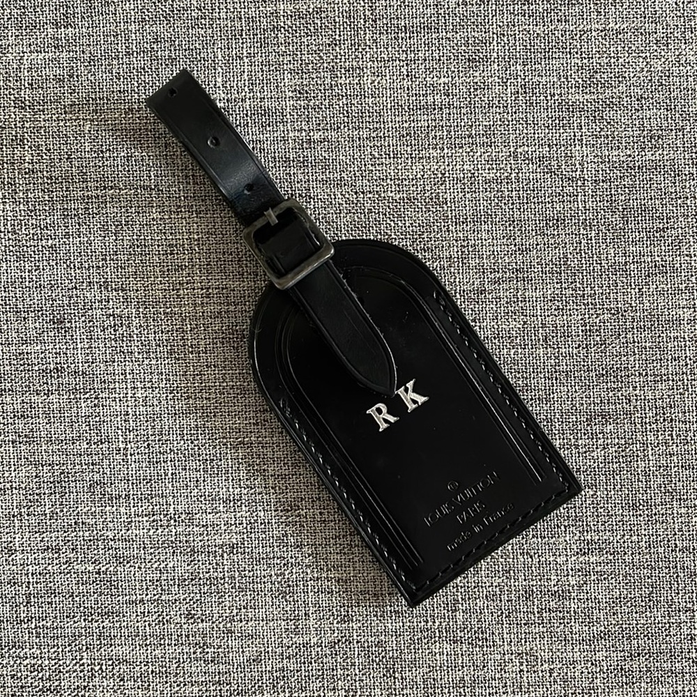 Louis Vuitton black luggage tag customised with embossed initials “RK” in silver